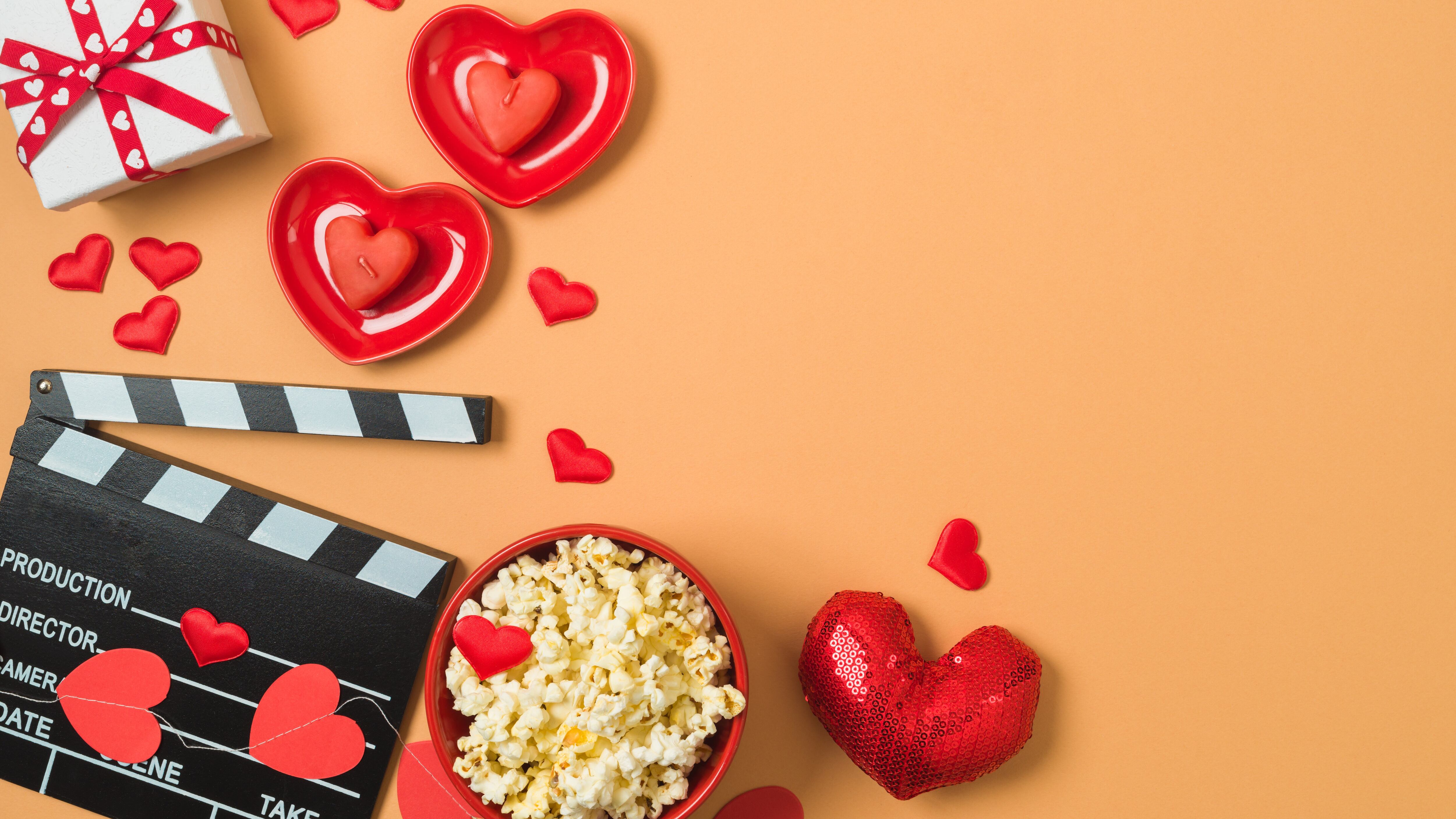 Happy Valentine's day and romantic movie concept with movie clapper board, heart shapes and popcorn